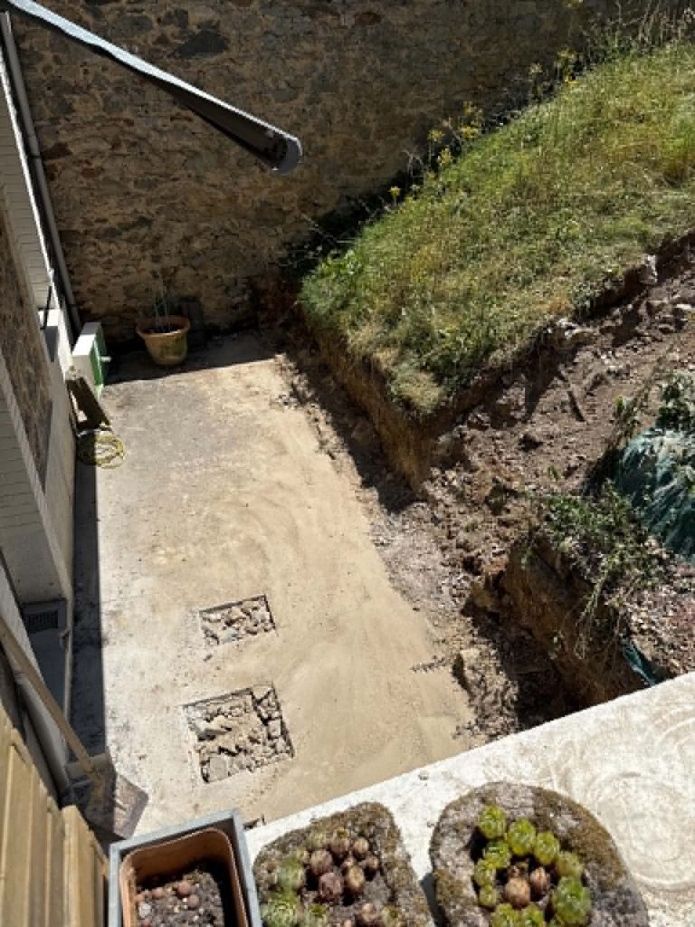Plateforme décaissée le long d’une maison, talus repris