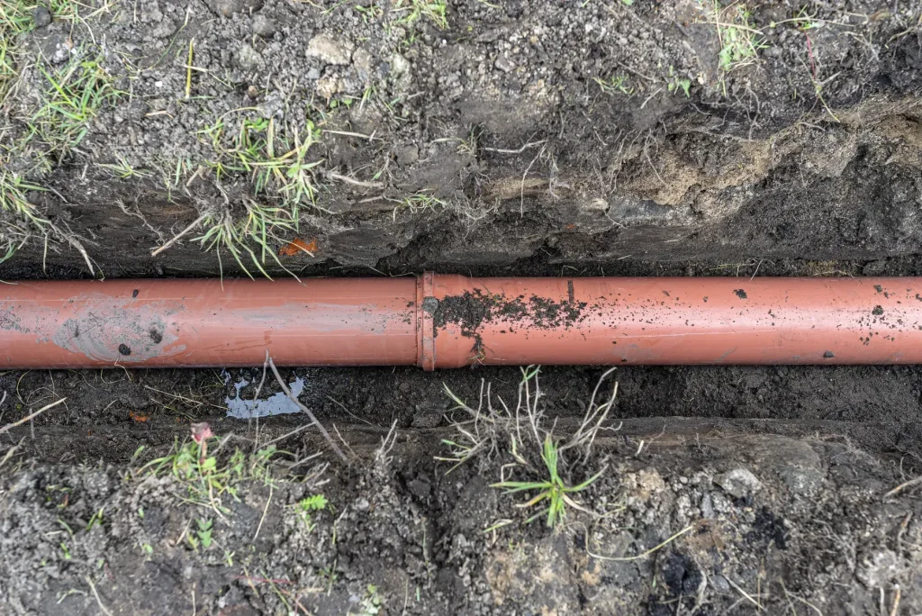 Canalisation d’eaux usées en PVC orange posée au fond d’une tranchée
