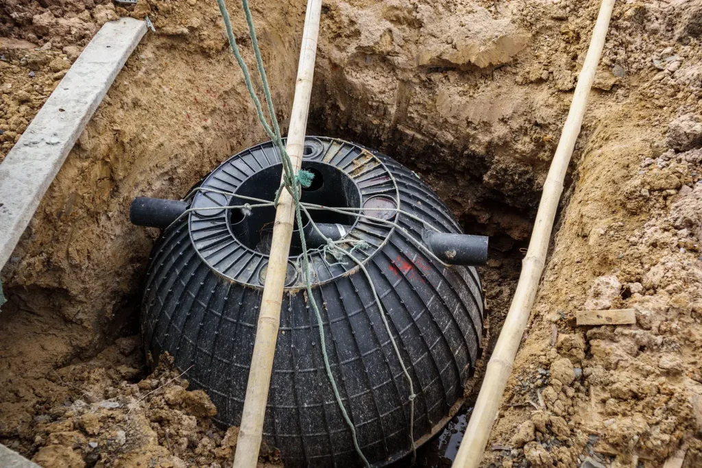 Cuve d’assainissement en plastique nervuré calée dans sa fouille avant remblaiement